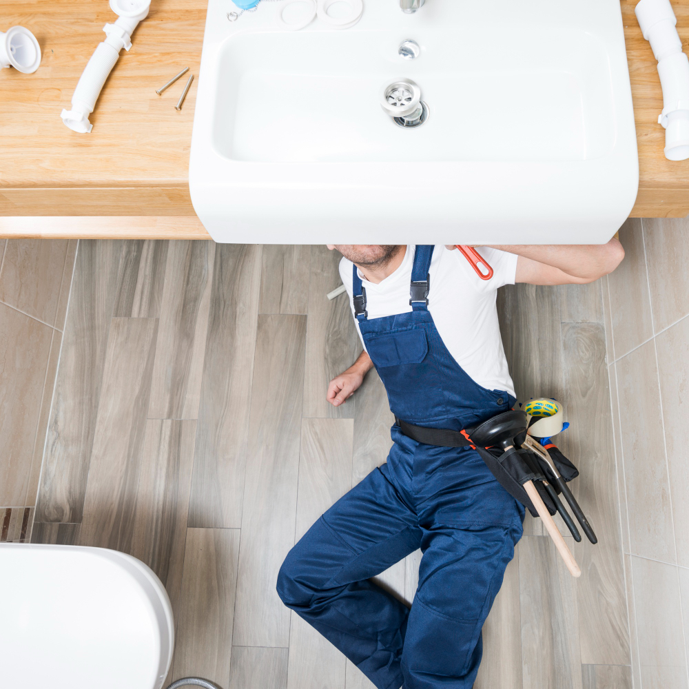 plombier au sol qui installe un lavabo dans une salle de bain